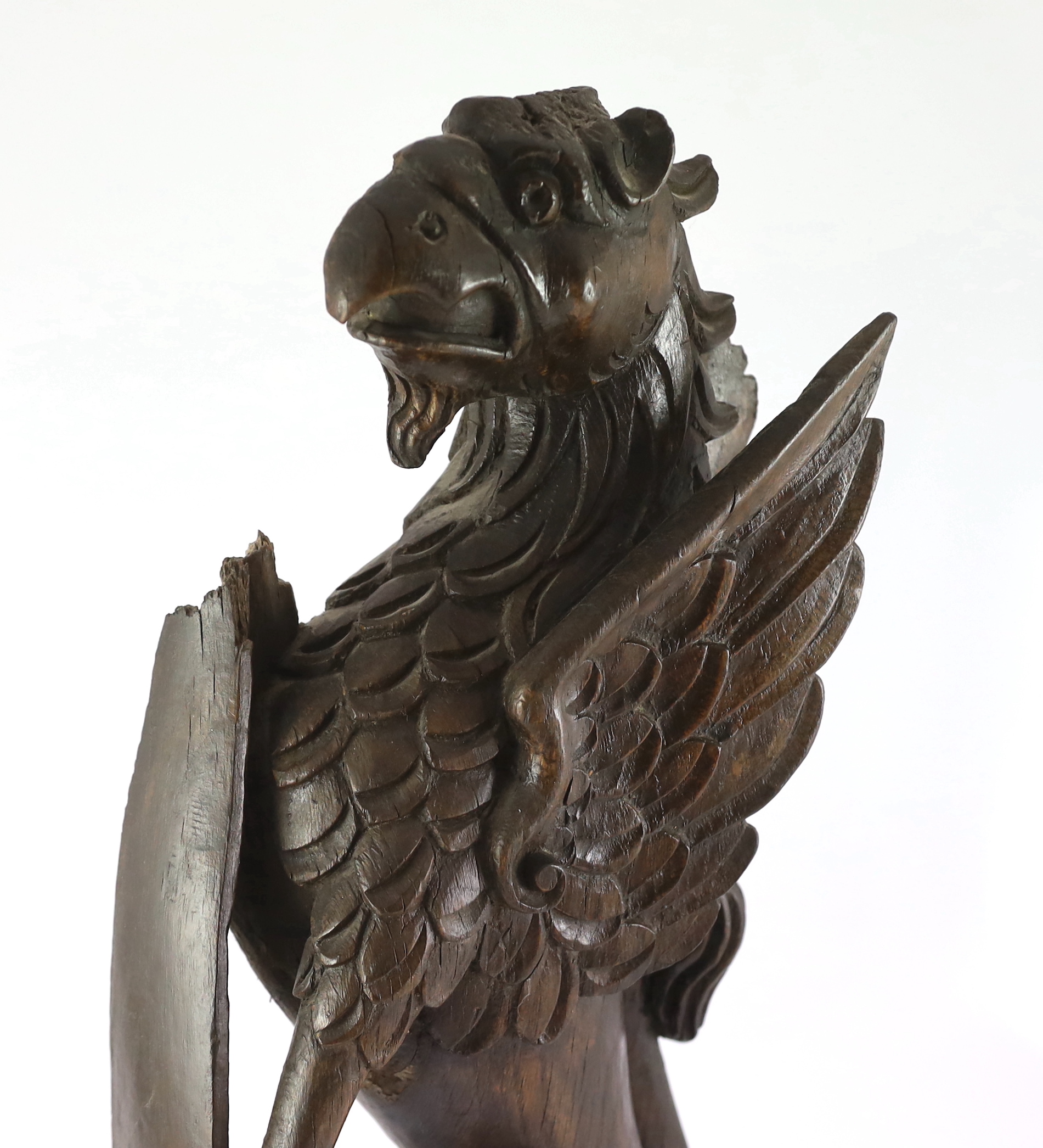 A 16th century Dutch carved oak model of a griffin rampant holding a shield